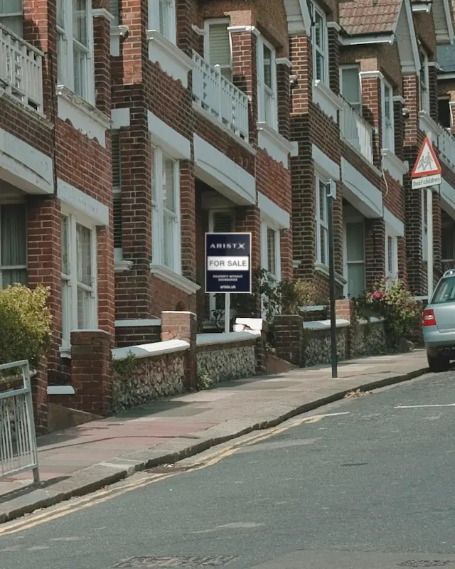 A terrace of red brick houses with an ARISTX For Sale board outside one of them
